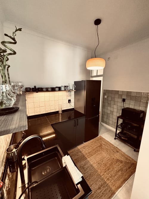 Modern kitchen in Royal Prince Garden Apartments Lisboa, featuring dark cabinets, tiled backsplash, pendant lighting, and