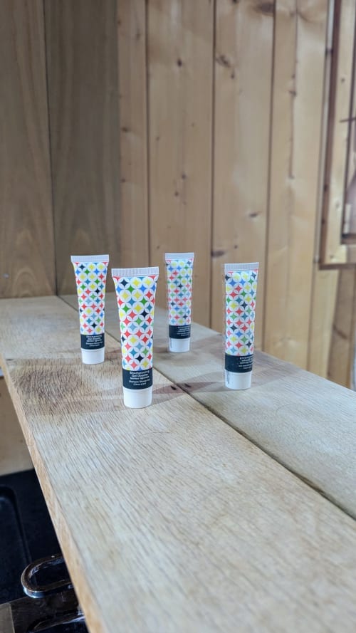 Quattro colorati tubi di articoli da toeletta con motivi a stella allineati su una superficie in legno presso il lodge Cabanes et Lodges du Belvédère