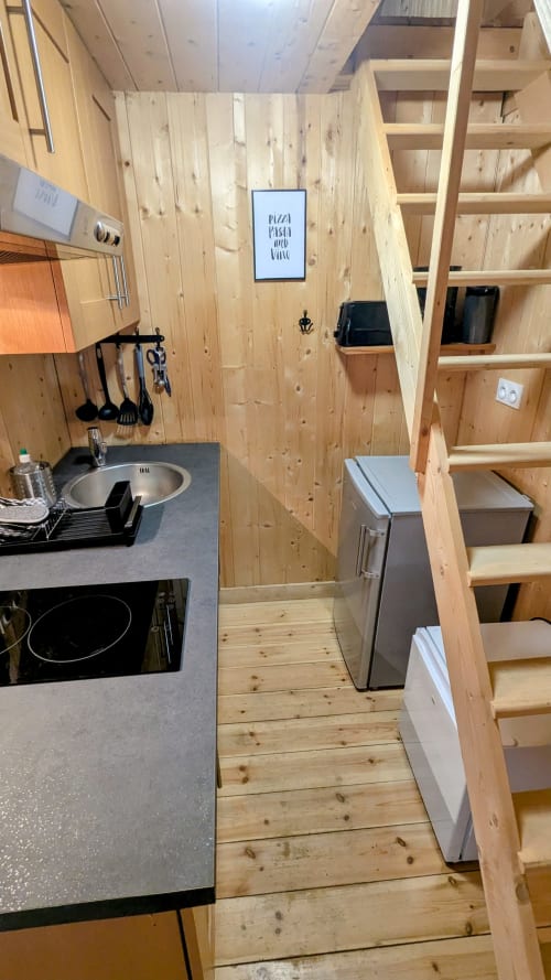 Cucina compatta in legno con stufa, lavello, scaffali e elettrodomestici nel lodge La Cormiere