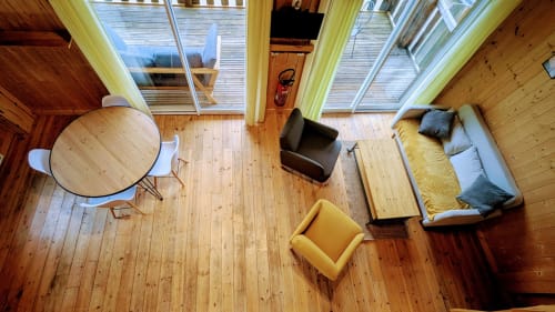 Interno di lodge moderno con pavimenti in legno, tavolo da pranzo, poltrona gialla, letto e lucernari con vista su Serrières-sur-Ain