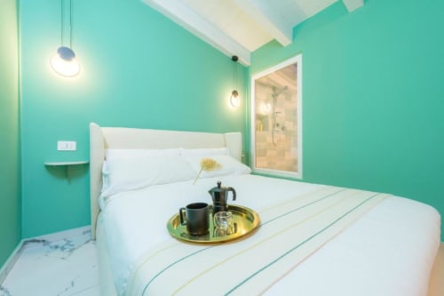 Letto comodo con topper, vista doccia dal letto, elementi rotondi, caffettiera 