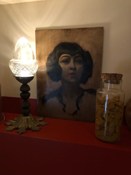 Élégante composition de chevet au Domaine de l'Ocrerie : lampe en cristal, portrait et pot décoratif sur surface rouge