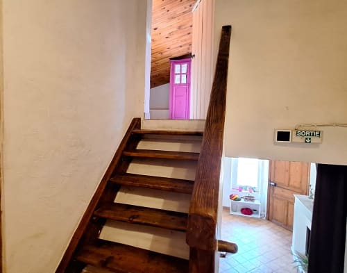 Escalier en bois dans la chambre mansardée de La Bergerie Du Moulin, Taradeau, avec porte rose visible au palier