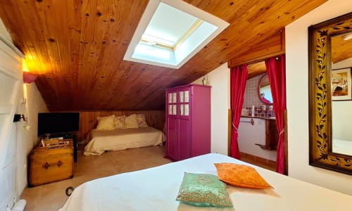 Chambre cosy sous les combles à La Bergerie Du Moulin avec plafond en bois, puit de lumière et touches rouges