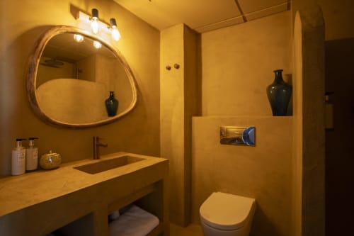 Baño moderno en Formentera Especial con paredes de azulejos dorados, lavamanos tipo vasija, espejo iluminado y jarrones decorativos oscuros