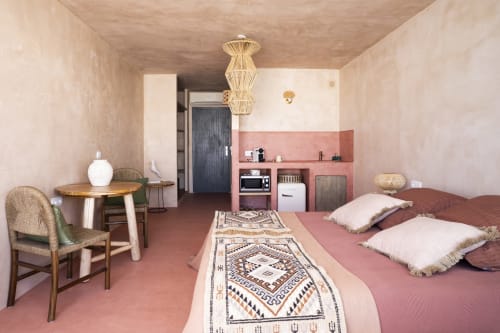 Estudio Luna en Formentera Especial con pared de acento rosa, lámpara colgante tejida y elementos de diseño costero