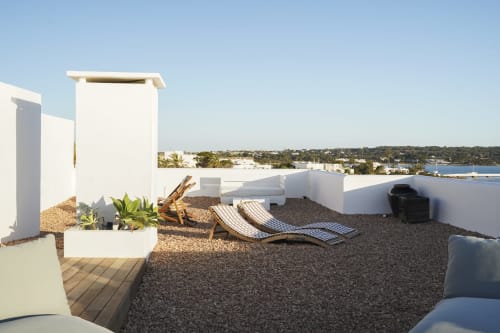 Terraza moderna en la azotea de Formentera Especial con vistas al mar, tumbonas rayadas, arquitectura blanca y paisaje costero