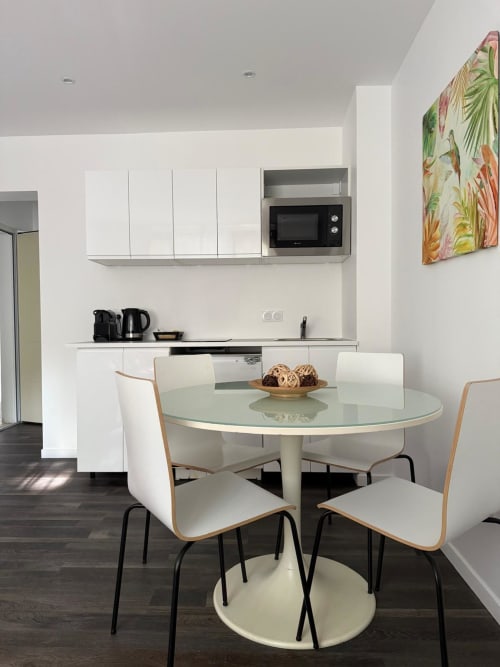 Espace cuisine-salle à manger moderne à l'Appart Hôtel Panambi avec table ronde, chaises blanches et kitchenette équipée