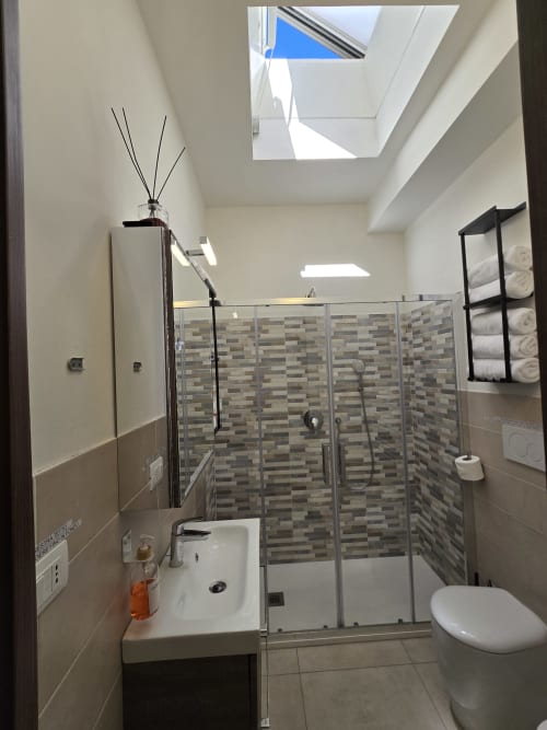 Moderna kupaonica u Raymihome Torinu sa krovnim prozorom, walk-in tuš kabinom, pločicama na zidovima, umivaorom i WC-om
