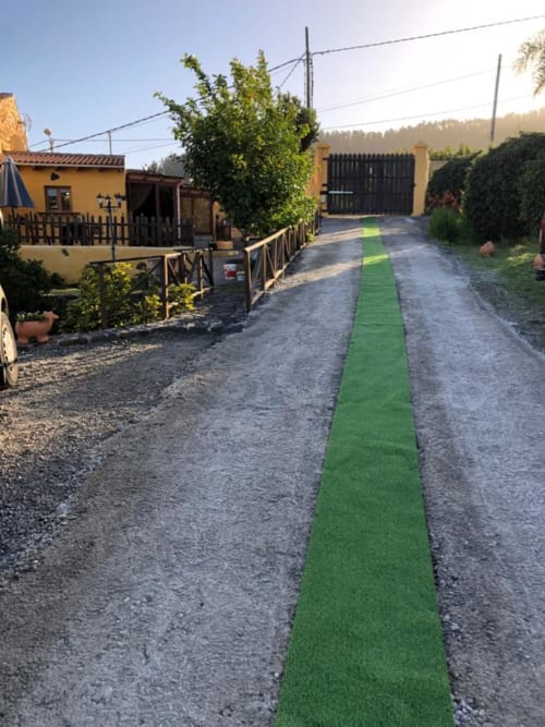 Green pathway through Casonas de Marengo cottage grounds in Icod de los Vinos with yellow buildings and mountain views