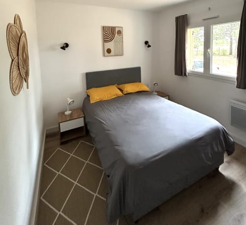 Chambre moderne à ALMA ROSSA, Lecci avec lit gris, coussins jaunes, décoration murale en rotin et vue sur le jardin