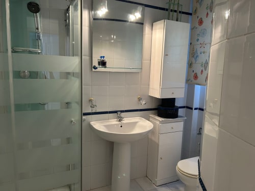 Baño moderno del apartamento SACORO en Marbella con lavamanos de pedestal, inodoro, ducha y paredes de azulejos blancos