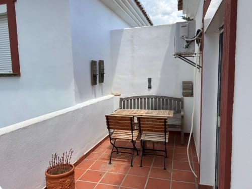Terraza privada del apartamento SACORO en Marbella con banco de madera, mobiliario de comedor y paredes blancas