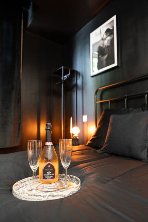 Champagne bottle and flutes in luxurious dark Bordeaux apartment with ambient lighting and framed artwork