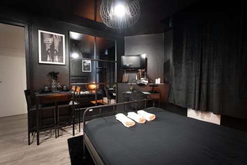 Modern dark bedroom with queen bed, work desk, and living area at Wellkhome Bordeaux