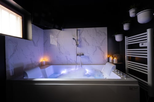 Luxurious Jacuzzi bathtub with ambient lighting in L'ÉCRIN NOIR apartment at Wellkhome Bordeaux