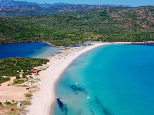 Baia turchese con spiaggia di sabbia bianca vicino alle Villas Lantana a Lecci, Corsica, circondata da colline verdi