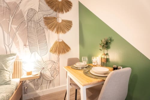 Wellkhome apartment dining area in Bordeaux with botanical wall art, wooden table, and green accent wall