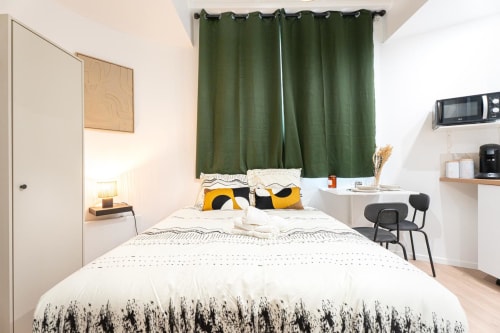 Wellkhome Smart Studio in Bordeaux: compact apartment with queen bed, yellow accents, green curtains, work desk, and