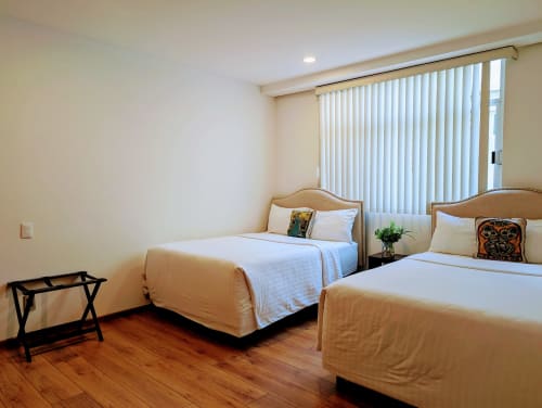 Dormitorio luminoso en Casa Donceles, Ciudad de México, con dos camas queen, ropa de cama blanca, pisos de madera y persianas verticales