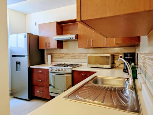 Cocina moderna en apartamento Casa Donceles con electrodomésticos de acero inoxidable, gabinetes de madera y encimeras de granito en México