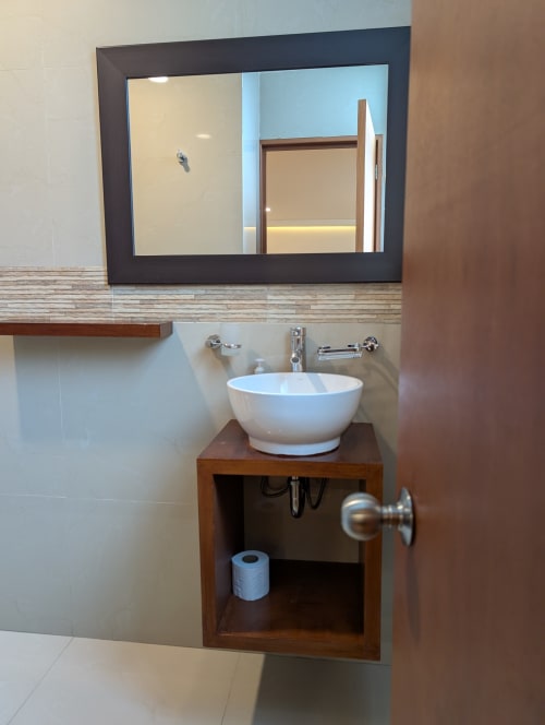 Lavamanos moderno con lavabo blanco, espejo con marco oscuro y tocador de madera en el apartamento Casa Donceles en Ciudad de México