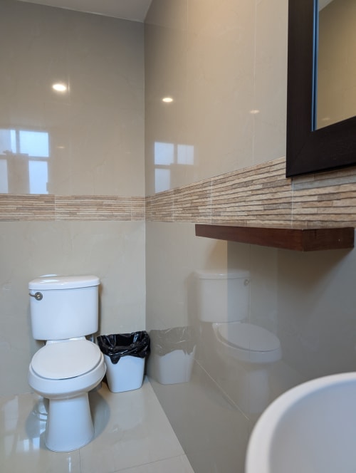 Baño moderno en apartamento Casa Donceles con inodoro blanco, paredes alicatadas, repisa de madera e iluminación empotrada en Ciudad de México