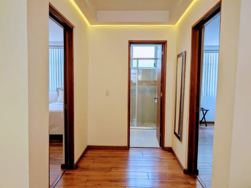 Pasillo luminoso del apartamento Casa Donceles con pisos de madera, puertas de cristal y vistas al océano desde el hotel en Ciudad de México