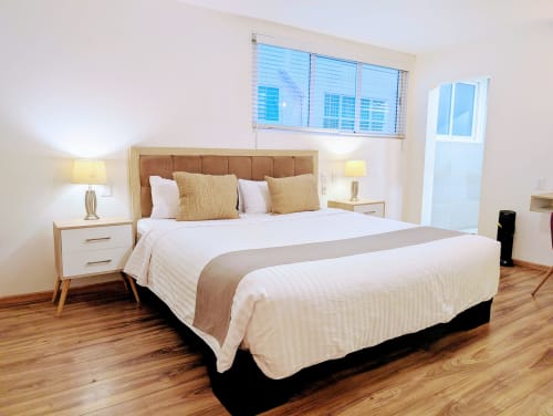 Moderna habitación king-size en Casa Donceles, Ciudad de México con pisos de madera, mobiliario contemporáneo y ventanas luminosas