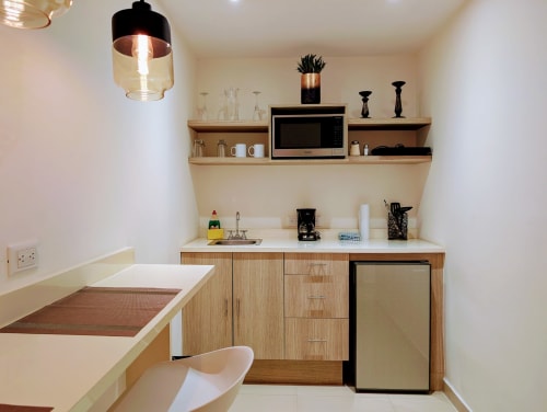 Cocina estudio moderna con gabinetes de madera, microondas, cafetera y mini nevera en Casa Donceles en la Ciudad de México