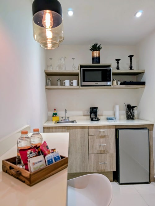Pequeña cocina moderna en el estudio Casa Donceles con estantes, microondas, minibar y iluminación colgante en Ciudad de México