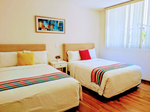 Dormitorio luminoso del apartamento Casa Donceles con dos camas, cabeceros de madera, caminos de cama a rayas coloridas y luz natural