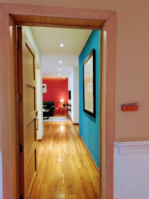 Pasillo con pisos de madera que conduce a un apartamento colorido en Casa Donceles, hotel de Ciudad de México con paredes azules y rojas visibles