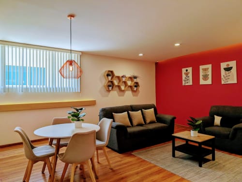 Sala moderna en Casa Donceles, Ciudad de México con sofá negro, comedor, pared de acento rojo y piso de madera