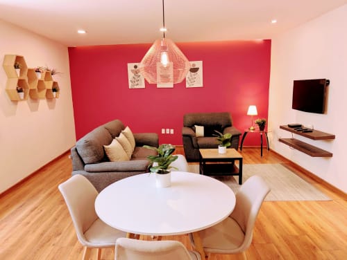 Sala de estar moderna en Casa Donceles, Ciudad de México con pared de acento rojo, sofá gris, mesa blanca y piso de madera.