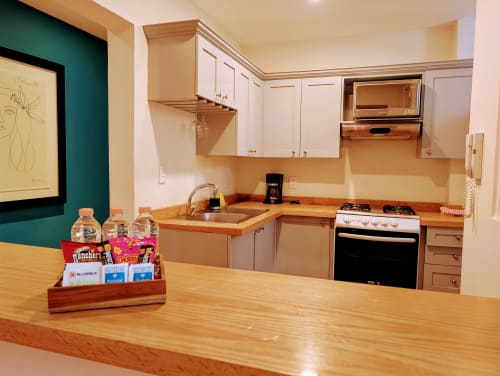 Cocina moderna en apartamento Casa Donceles, Ciudad de México, con encimera de madera, gabinetes blancos, estufa y pared de acento color turquesa