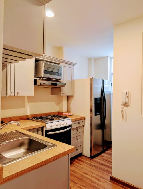 Cocina moderna del apartamento Casa Donceles en México, con electrodomésticos de acero inoxidable, encimeras de madera y acabados blancos