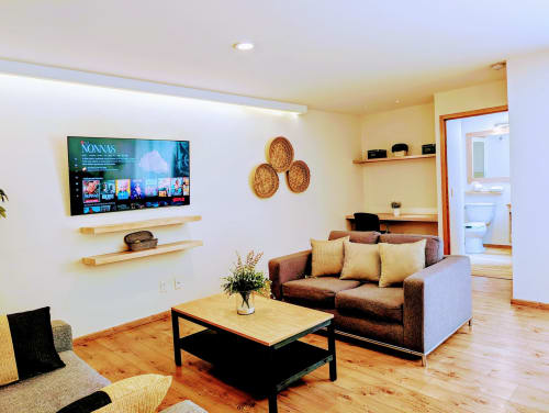Sala de estar moderna en el apartamento Casa Donceles, Ciudad de México, con sofá marrón, mesa de madera y TV montado en la pared