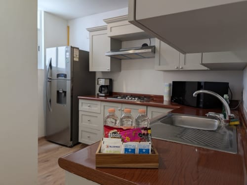 Cocina moderna del apartamento Casa Donceles en México, con fregadero de acero inoxidable, estufa, encimeras de madera y equipada