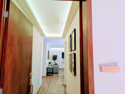 Pasillo moderno del apartamento 3 Casa Donceles con puertas de madera, luces LED en el techo y vista al salón con planta