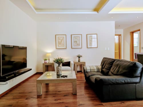 Sala de estar moderna en el apartamento Casa Donceles en la Ciudad de México con sofá negro, mesa de centro de madera, TV y vista al patio