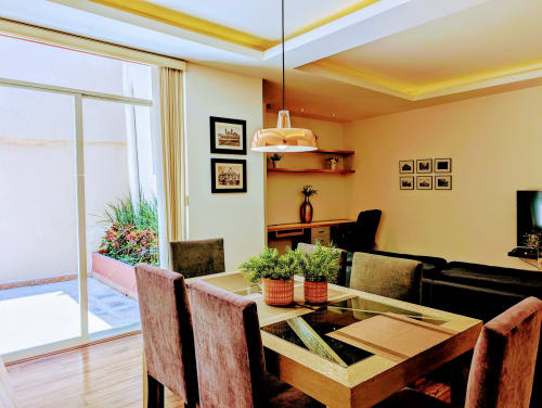 Sala moderna del apartamento Casa Donceles en Ciudad de México, con mesa de comedor, sofá, escritorio, lámpara colgante y acceso a terraza