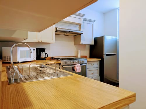 Cocina moderna del apartamento Casa Donceles en México, con encimeras de madera, electrodomésticos de acero inoxidable y área de comedor