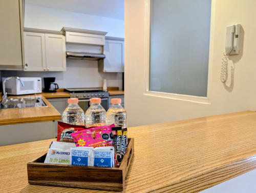 Bandeja de bienvenida en habitación con botellas de agua y snacks sobre mostrador de madera en apartamento Casa Donceles, Ciudad de México