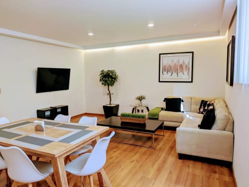 Sala moderna con sofá color crema, mesa de comedor, televisión y planta verde en Casa Donceles, Ciudad de México