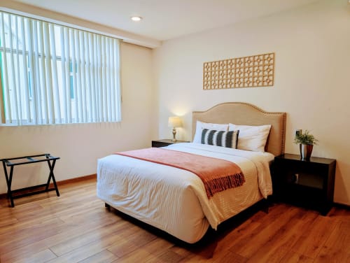 Espaciosa habitación en Casa Donceles, Ciudad de México, con cama queen, cabecera tapizada, mesita negra y lámpara.