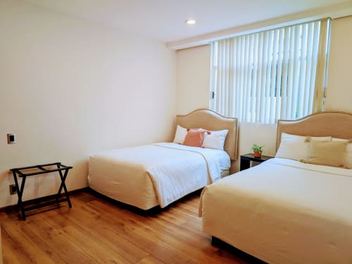 Habitación luminosa en Casa Donceles, Ciudad de México con dos camas, piso de madera y persianas verticales