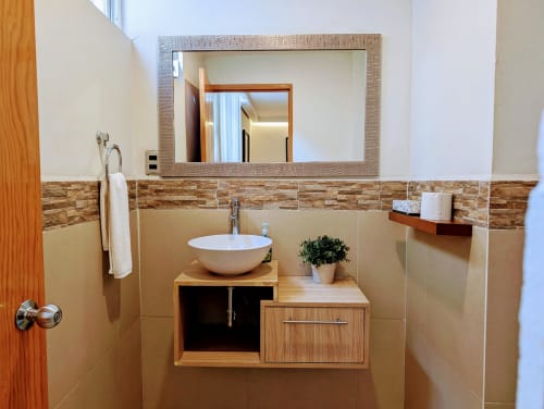 Baño moderno en Casa Donceles, Ciudad de México, con lavamanos de cerámica, espejo enmarcado, mosaico de piedra y madera