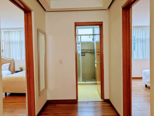 Pasillo luminoso con puertas enmarcadas en madera en el apartamento Casa Donceles de la Ciudad de México, conectando dormitorios y baño
