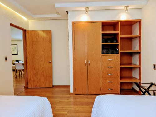 Dormitorio moderno en Casa Donceles, Ciudad de México, con armarios de madera, estantes, dos camas y piso de madera.